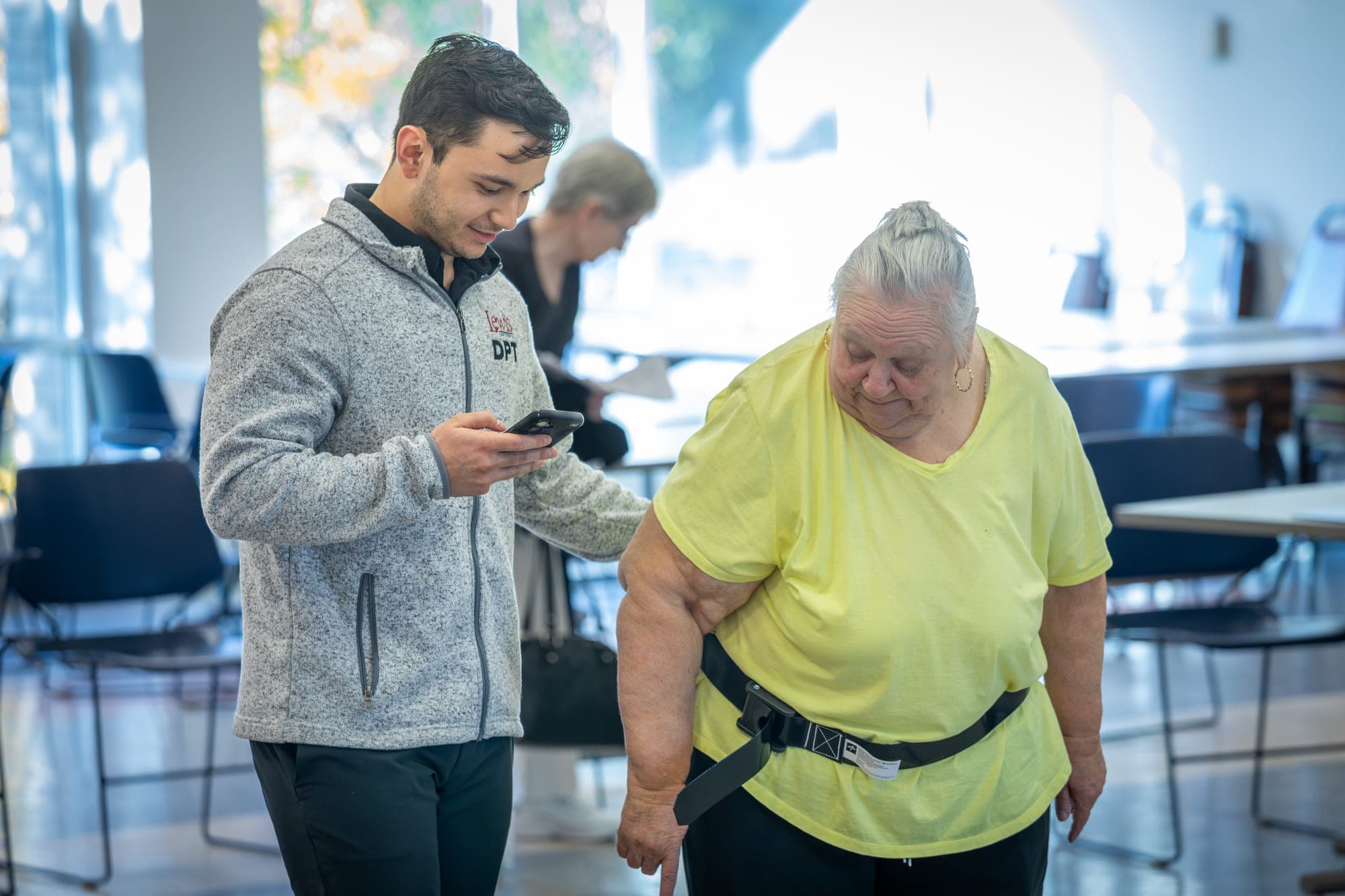 Student helping a woman fitted with a gait harness during a hands-on campus demonstration