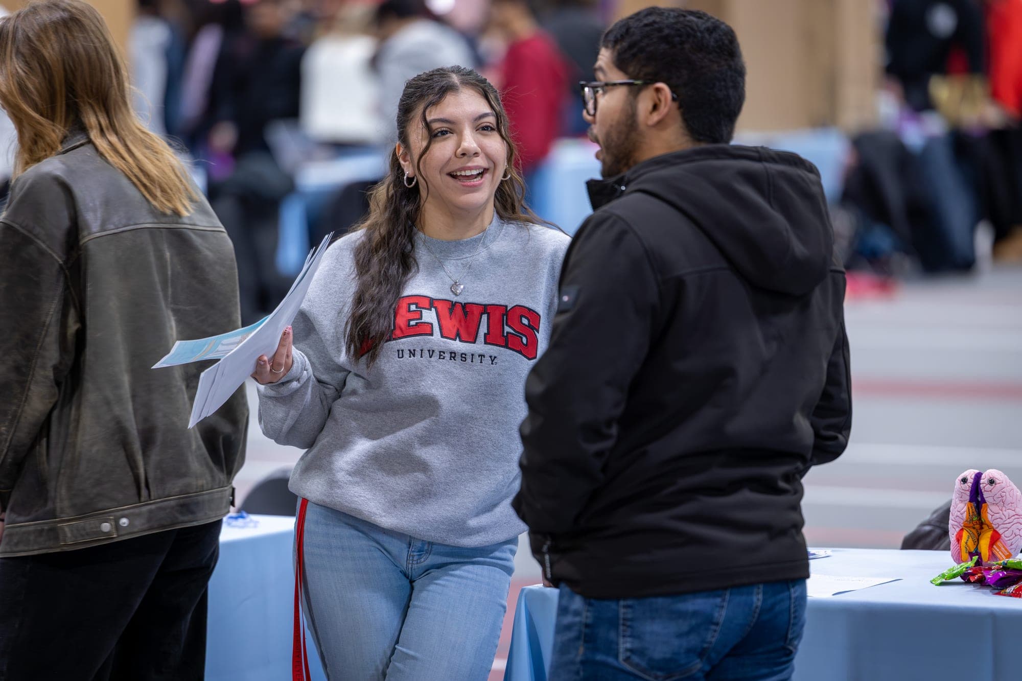 Lewis University student in a Lewis sweatshirt laughing with a classmate at a campus event