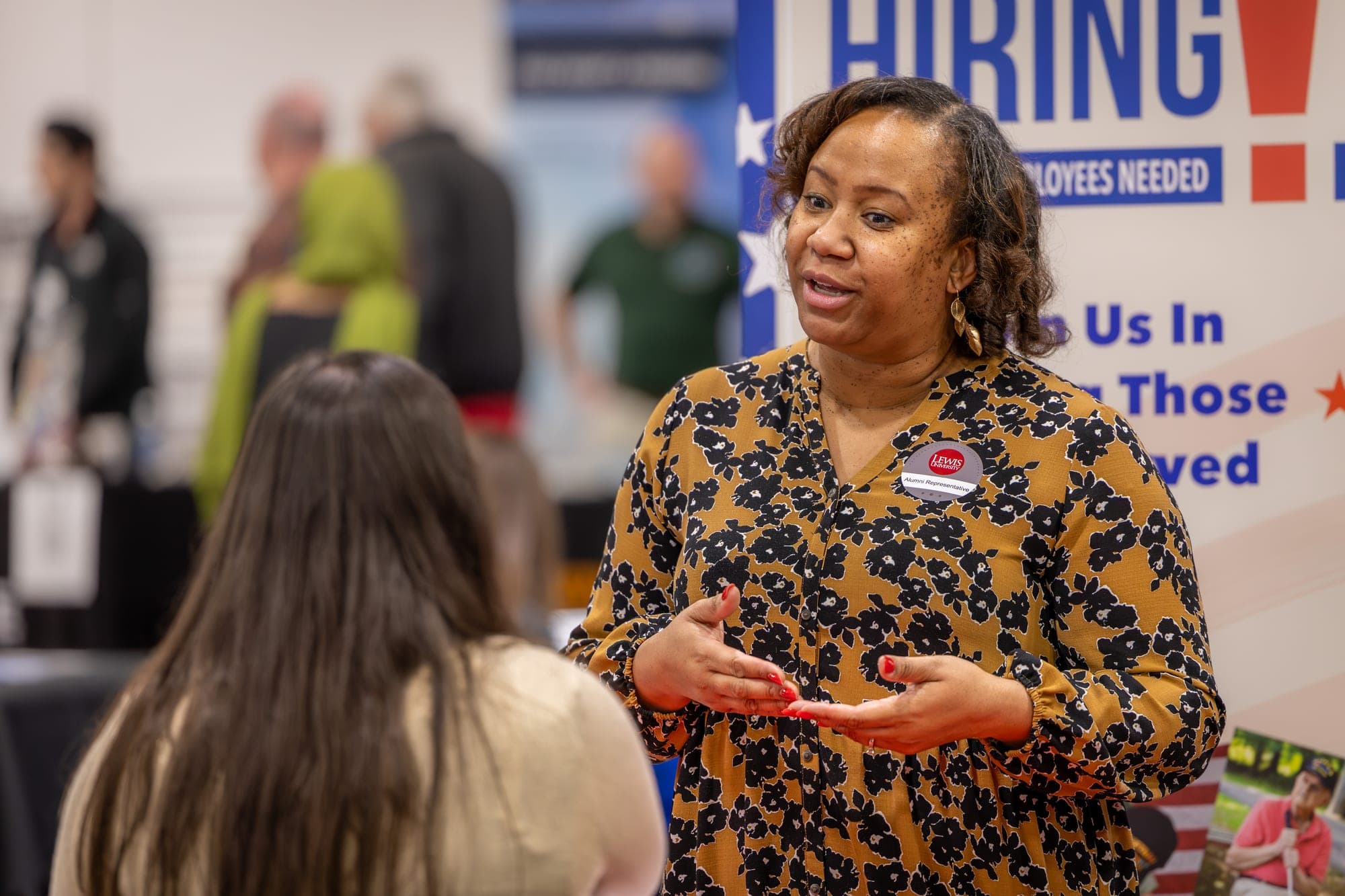 Speaker gesturing while talking with attendees at a career and hiring fair